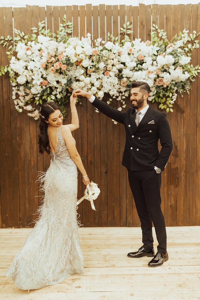 Bride and groom enjoying a dance at their wedding with floral backdrop.