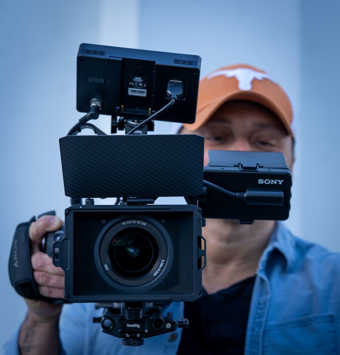 Cinematographer holding a Sony video camera, showcasing advanced filming equipment.